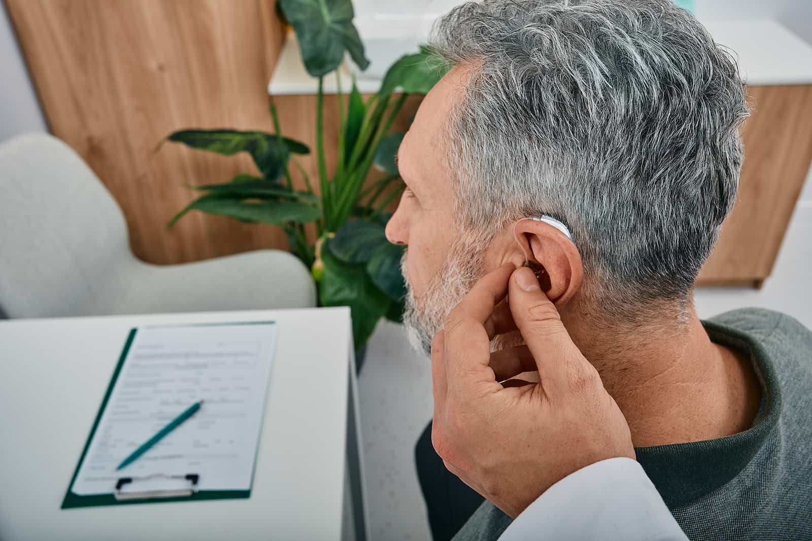 Audiologist Fits A Hearing Aid On Deafness Mature Man Ear While